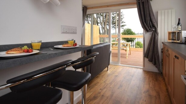 Una cocina moderna con barra, una mesa de comedor y vistas al exterior.