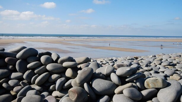 Una playa con piedras y cielo despejado.