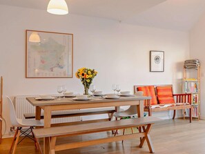 A dining area with a wooden table set for four, a bench, and a bookshelf with books and magazines. - 3 Bed in Camber (oc-bt011) (Camber)