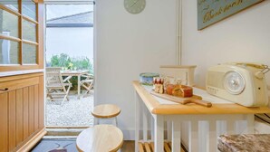A kitchen with a wooden table, a clock, and a vintage radio. - 2 Bed in Cheltenham (oc-46677) (Bourton-on-the-Water)