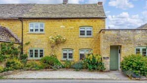 A stone building with a green door, multiple windows, and a 'NO PARKING' sign. - 2 Bed in Cheltenham (oc-46677) (Bourton-on-the-Water)