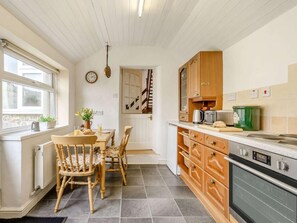 Eine Küche mit Holzausstattung, einem Esstisch mit Stühlen, einem Heizkörper und einer Uhr an der Wand.