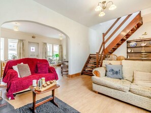 Ein Wohnzimmer mit einem roten Sofa, einem beigen Sofa, einem Holztisch und einer Treppe mit Holzhandläufen.