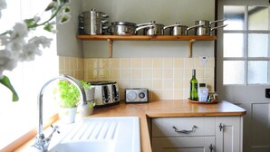 Uma cozinha com pia, torradeira, rádio e uma estante com panelas.
