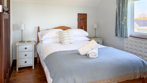 Quarto com uma cama, duas mesas de cabeceira, um guarda-roupa de madeira e uma janela com cortinas.