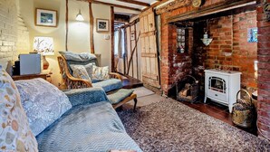 Een gezellige kamer met een bed, een stoel, een open haard en een rustieke bakstenen muur.