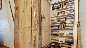 Een houten deur in landelijke stijl, met een metalen handgreep, naast een boekenplank vol boeken.