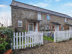 A stone building with a white picket fence, a bench, and a gravel driveway. - 4 Bed in Bideford (oc-46840) (Pusehill)