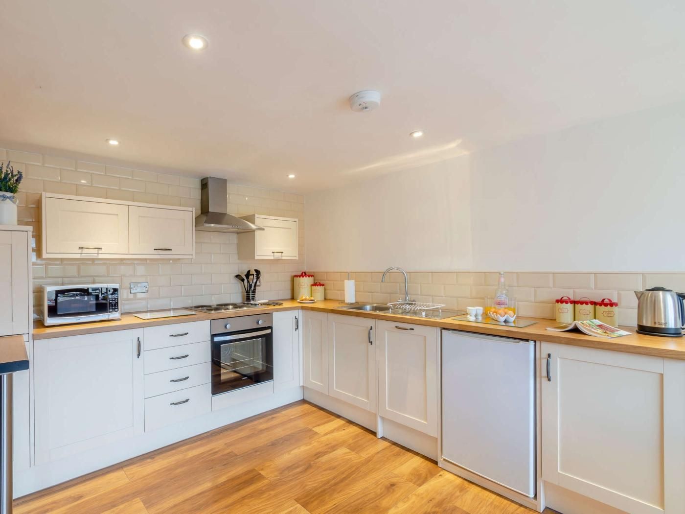 A modern kitchen with white cabinets, a microwave, oven, and a sink.