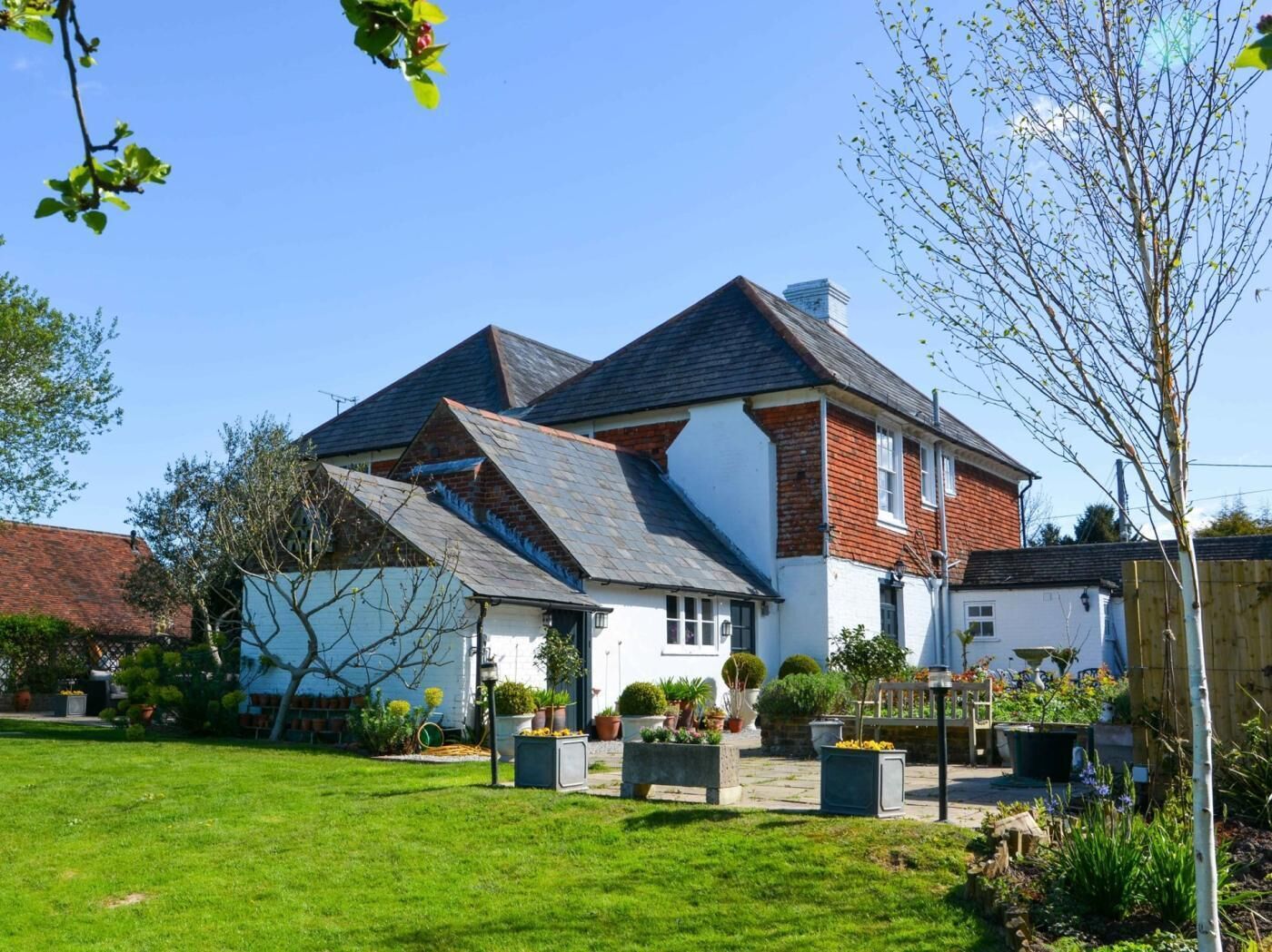 A two-story house with a sloped roof, a brick exterior, and a well-maintained garden with various plants and a lawn.