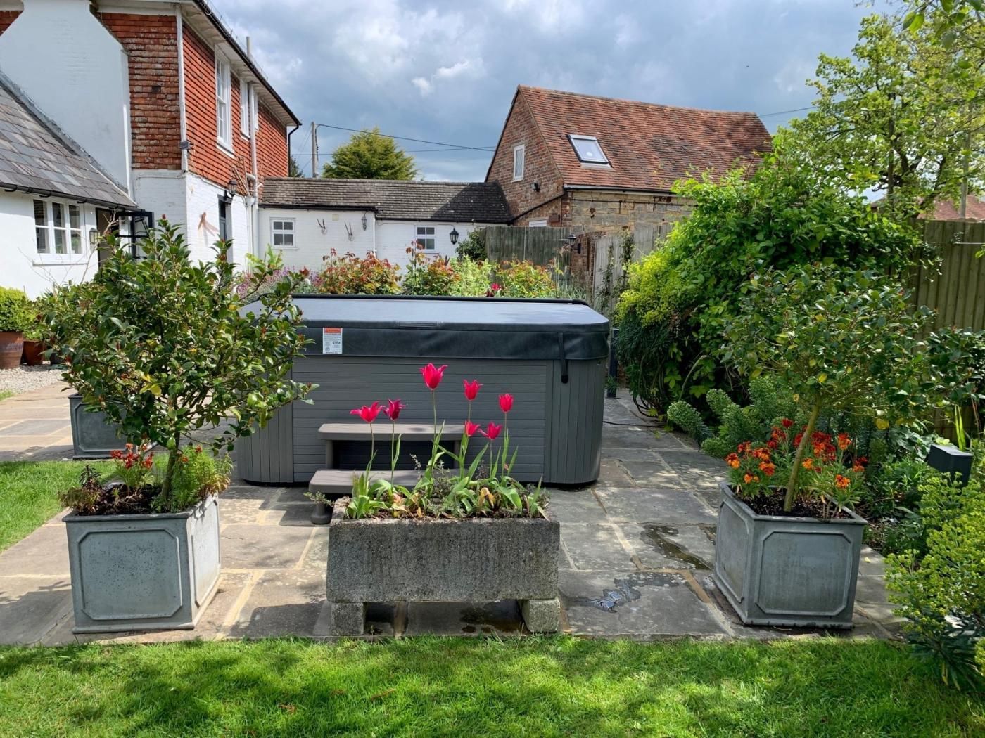 Een tuin met een jacuzzi, potplanten en een bank.