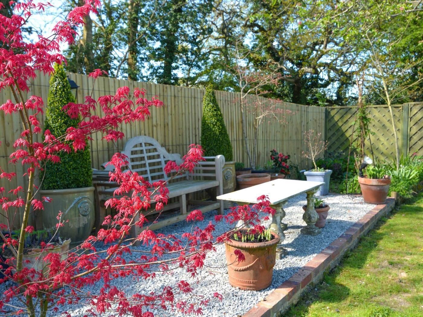 A garden patio with a bench, table, and potted plants.