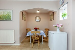 A dining area with a table set for four, a white radiator, and a small white refrigerator.