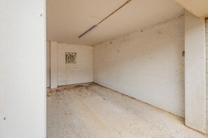 Ein Zimmer mit weißen Ziegelwänden, einem einzigen Fenster mit Metallgitter und einem Betonboden.