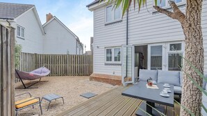 Eine Terrasse mit Gartenmöbeln, einem Hängesessel und einem Tisch mit Tassen und Untertassen.