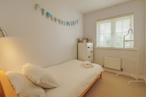 A bedroom with a bed, a radiator, a window with blinds, a wardrobe, and a wall-mounted shelf with books. - 3 Bed in Camber (oc-bt044) (Camber)
