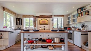 A modern kitchen with a central island, wooden flooring, and built-in appliances. - 5 Bed in Sturminster Newton (oc-76458) (Woodrow)