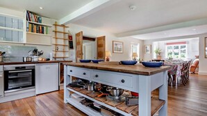 A modern kitchen with a central island, wooden cabinets, and a built-in oven. - 5 Bed in Sturminster Newton (oc-76458) (Woodrow)