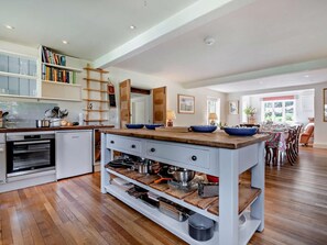 Eine moderne Küche mit einer zentralen Kochinsel, Holzschränken und einem eingebauten Backofen.
