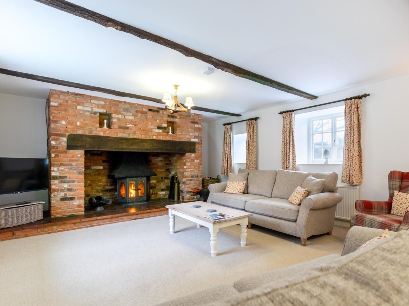 A living room with a brick fireplace, a sofa, a television, and a coffee table.