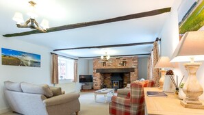 A living room with a sofa, a plaid chair, a fireplace, and a television. - 3 Bed in Hunstanton (oc-78821) (Hunstanton)