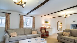 A living room with a sofa, armchair, coffee table, and a dining area with a table and chairs. - 3 Bed in Hunstanton (oc-78821) (Hunstanton)