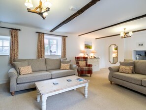 A living room with a sofa, armchair, coffee table, and a dining area with a table and chairs. - 3 Bed in Hunstanton (oc-78821) (Hunstanton)