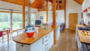 A spacious kitchen with wooden cabinets, a central island, and a dining area with chairs. - 4 Bed in Fort William (oc-78875) (Muirshearlich)
