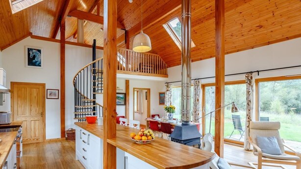 A spacious kitchen with a wooden island, a spiral staircase, and a large dining area with outdoor seating. - 4 Bed in Fort William (oc-78875) (Muirshearlich)