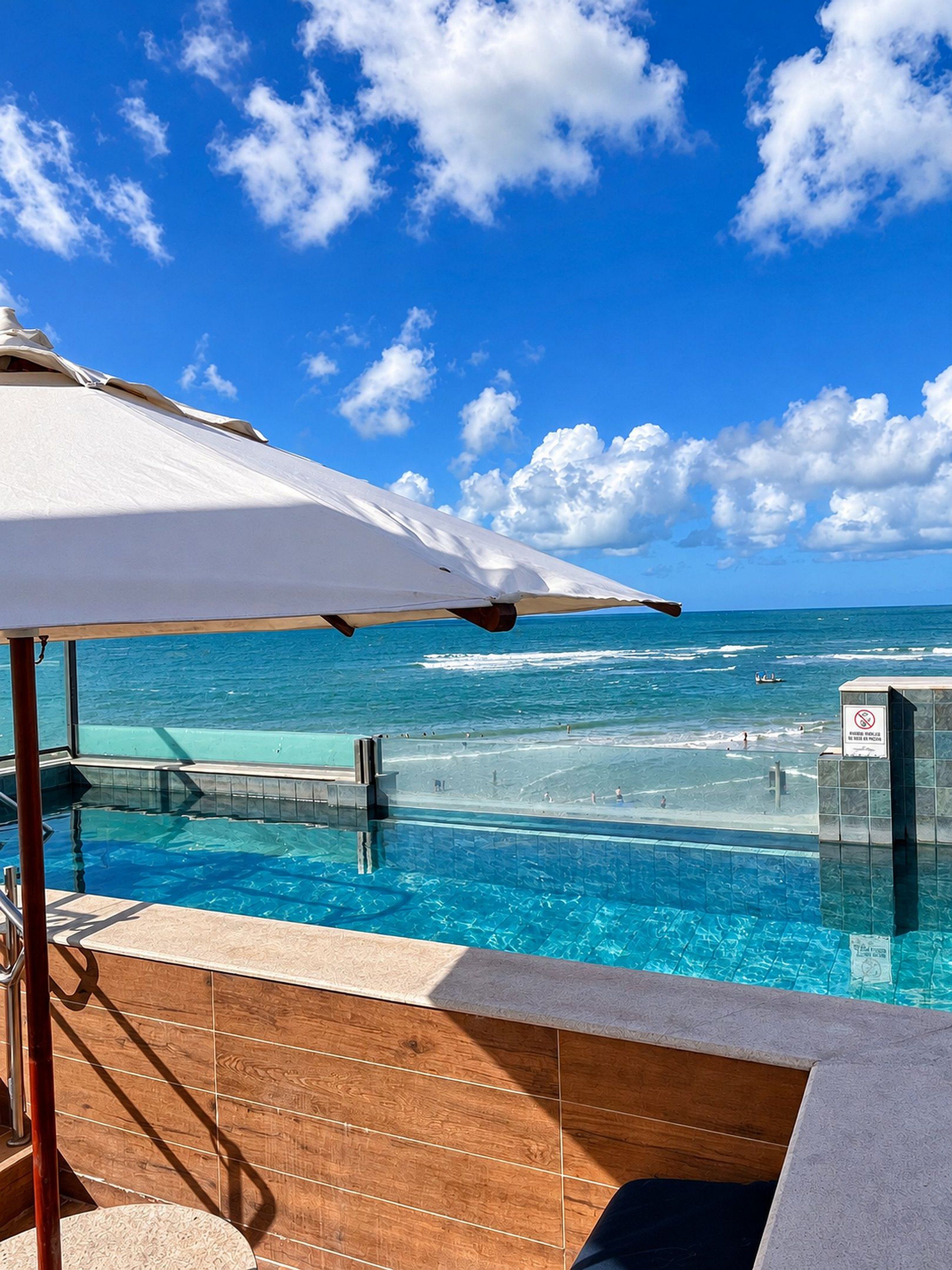 Un área junto a la piscina con vistas al océano y un cielo despejado.