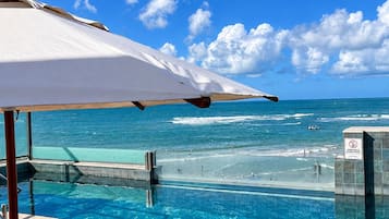 Un área junto a la piscina con vistas al océano y un cielo despejado.