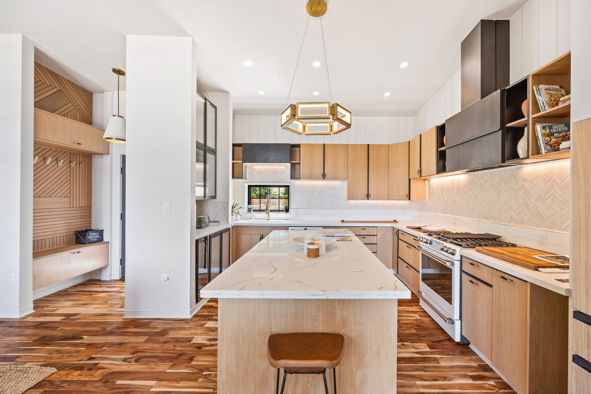 Een moderne keuken met een centraal eiland, houten kastjes en een ingebouwde kookplaat.