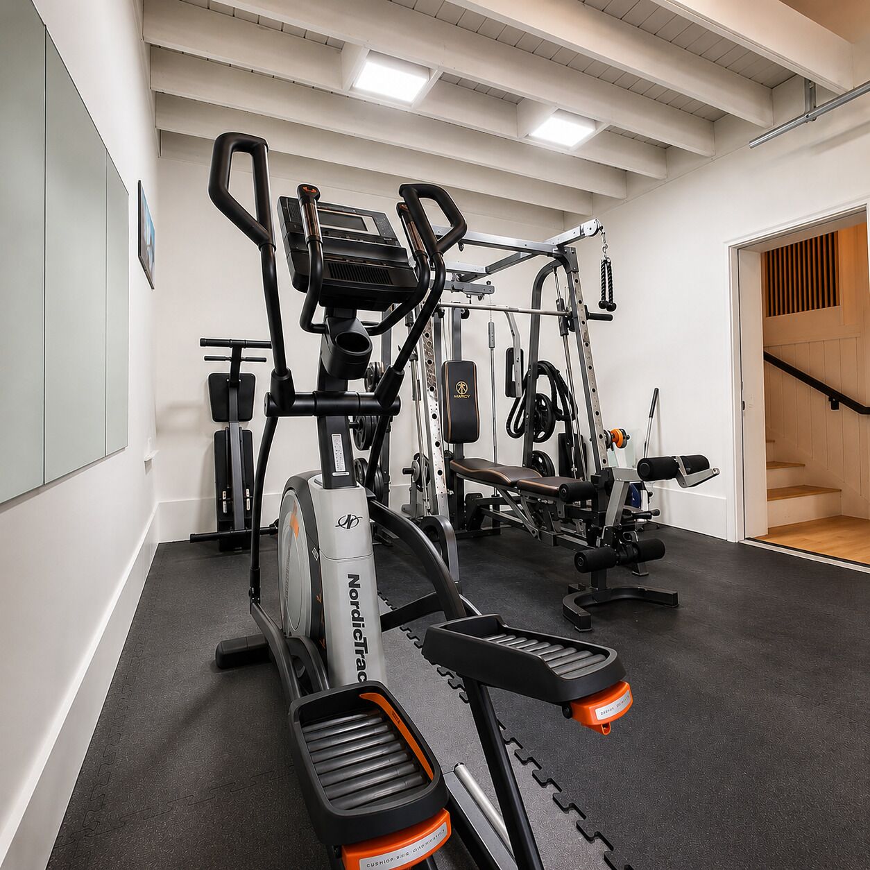 A gym with cardio machines, weightlifting equipment, and a bench.
