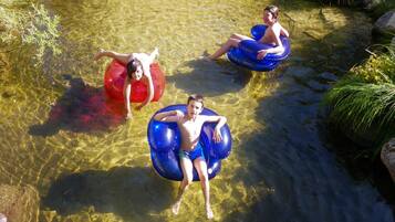 Three people floating in clear water using inflatable tubes.