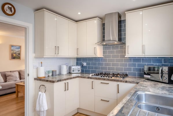 A modern kitchen with white cabinets, a gas stove, a microwave, and a toaster.