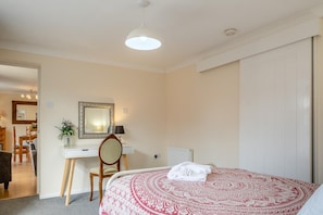 A bedroom with a bed, a desk, a chair, a mirror, and a radiator.