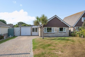 A residential property with a paved driveway, a garage, and a lawn.