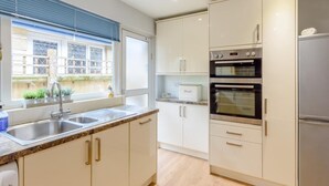 A modern kitchen with white cabinetry, a stainless steel sink, a built-in oven, and a refrigerator. - 3 Bed in Freshwater (oc-79039) (Freshwater)