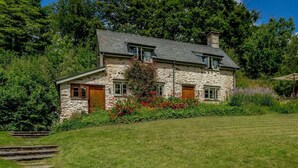 Ein Haus aus Stein mit einem geneigten Dach, einer Veranda und einer Steintreppe, die zum Eingang führt.