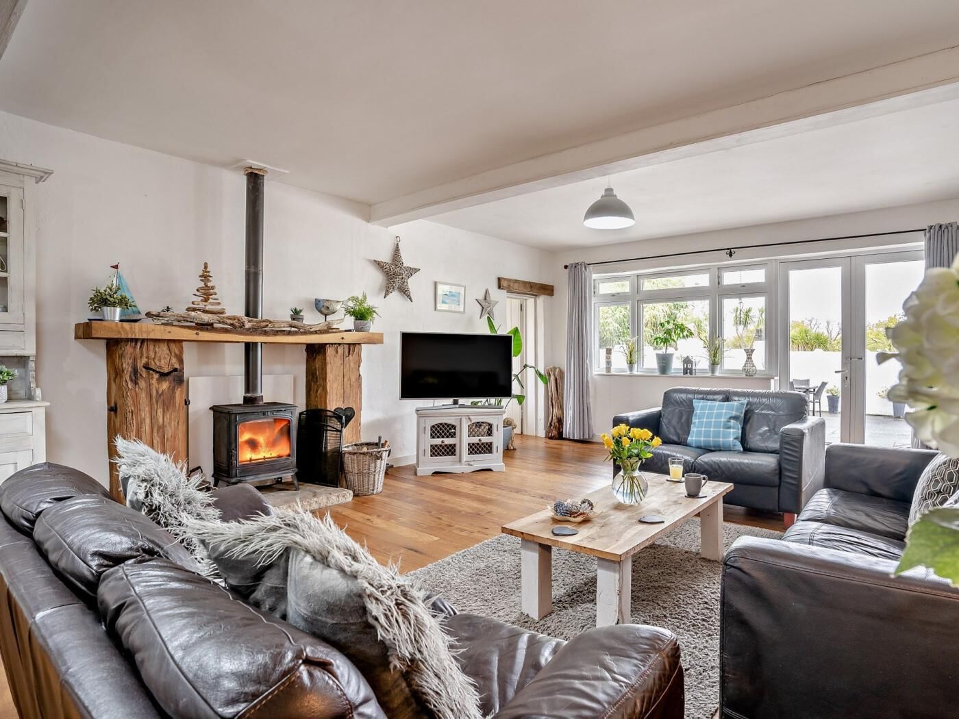 A living room with a fireplace, leather sofas, a television, and a large window.
