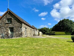 A stone building with a sloped roof, a gravel driveway, and a well-maintained lawn. - 2 Bed in Newport (oc-78803) (Llwyngwair Manor)