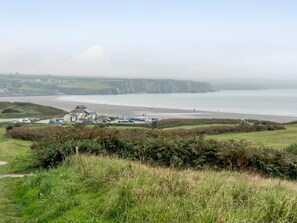 A coastal view with a building, grassy areas, and cliffs. - 2 Bed in Newport (oc-78803) (Llwyngwair Manor)