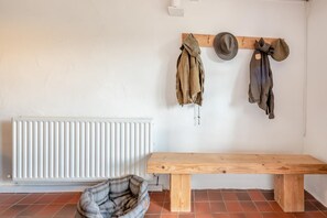 A room with a white radiator, a wooden bench, and a bed with a plaid blanket. - 2 Bed in Newport (oc-78803) (Llwyngwair Manor)