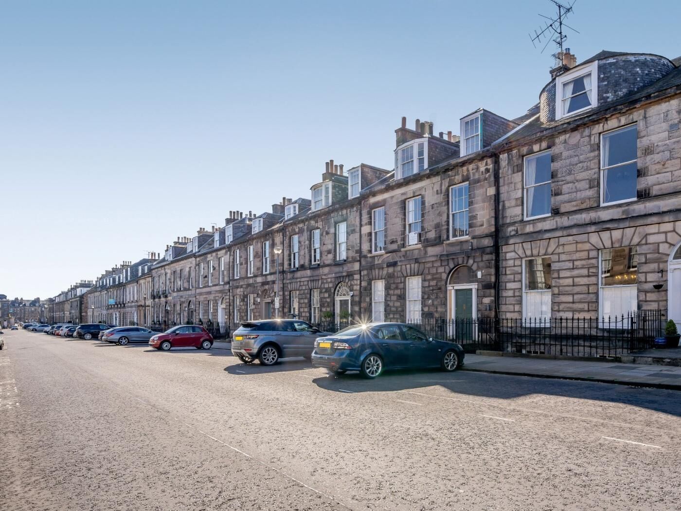 A row of terraced houses with parked cars on the street.