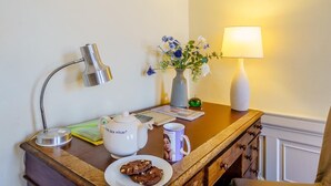 A wooden table with a white teapot, a mug, a plate with cookies, a lamp, and a vase with flowers. - 3 Bed in Edinburgh (oc-79008) (Edinburgh)