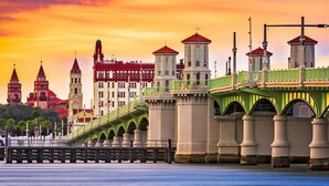 Un ponte con ringhiere verdi e una torre dell'orologio sullo sfondo.