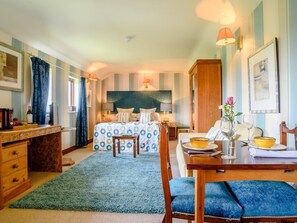 A hotel room with a bed, a desk, a dining table, and a small kitchen area.