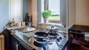 Eine moderne Küche mit einem Gasherd, einer Spüle und einem Fenster mit Blick ins Freie.