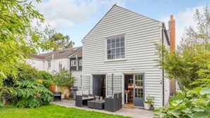 Een tweelaags huis met een patio, een eettafel en zitplaatsen buiten.