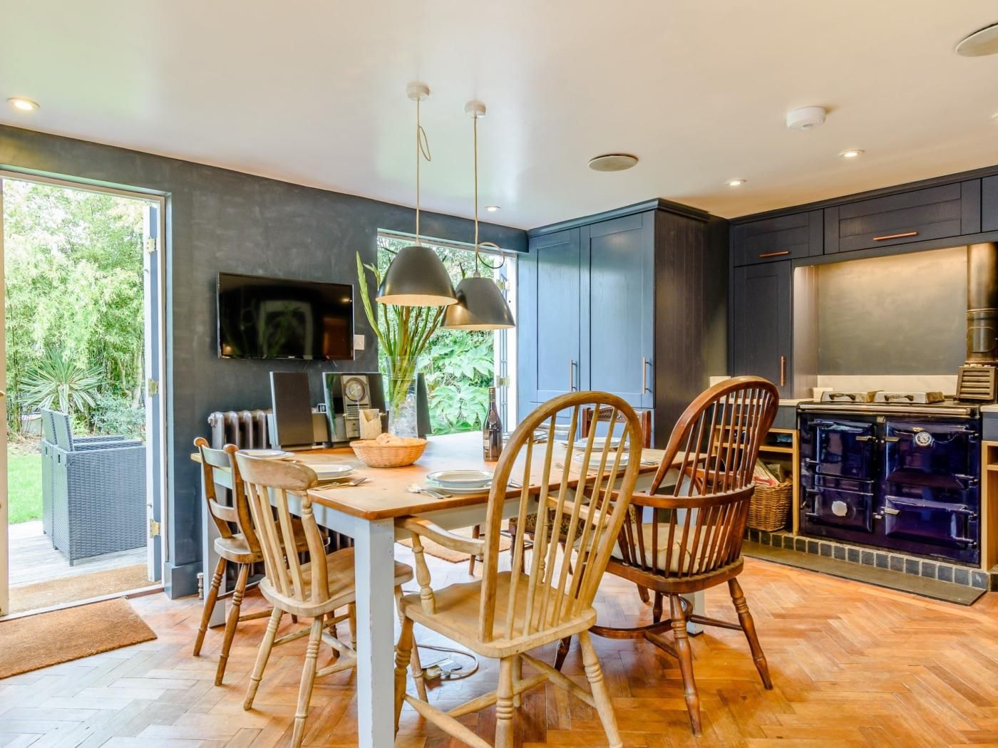 A modern kitchen with dark cabinets, a built-in stove, and a dining area with wooden chairs and a table.